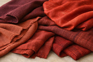 Close-up of vibrant red Indian handloom textiles showcasing rich crimson and vermillion shades with intricate traditional weaving patterns