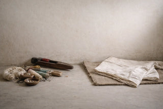 Traditional handloom textiles folded beside artisan tools and natural materials on a workshop floor