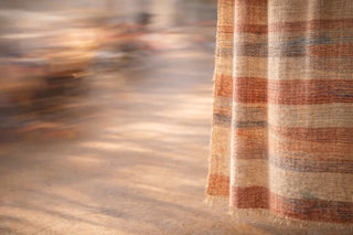 Handwoven textile with earthy striped pattern in warm tones, showcasing traditional handloom craftsmanship and the timeless quality of slow-made textiles