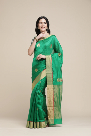 Woman wearing a green saree with gold border on a beige background