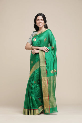 Woman wearing a green saree with a beige background