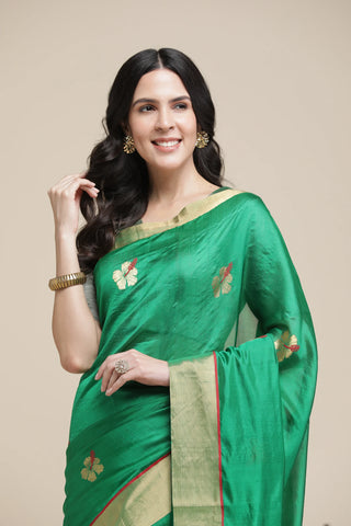Woman wearing a green saree with floral patterns on a beige background