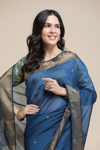 Woman wearing a blue saree with a beige background