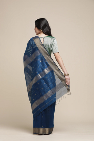 Woman wearing a blue saree with a beige background
