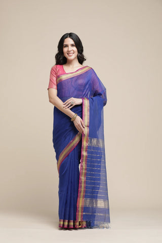 Woman wearing a blue saree with a pink blouse against a beige background
