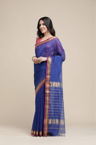 Woman wearing a blue saree with a red blouse against a beige background