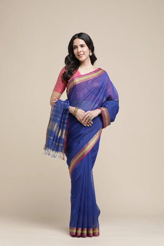 Woman wearing a blue saree with a pink blouse against a beige background
