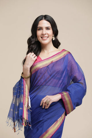 Woman wearing a blue saree with a pink blouse against a beige background