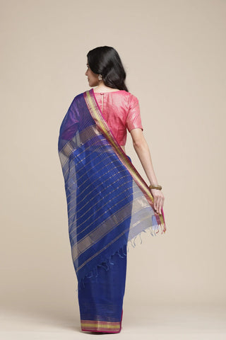 Woman wearing a blue saree with a pink blouse against a beige background