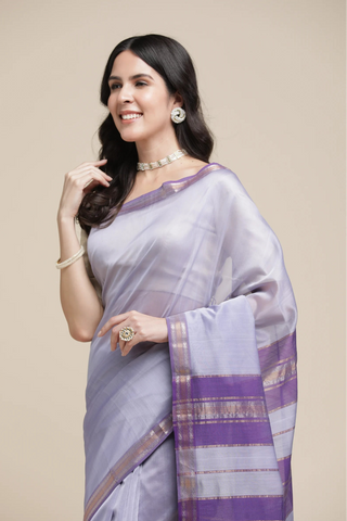 Woman wearing a light purple saree with a subtle pattern on a beige background