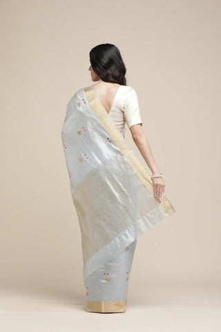Woman wearing a light blue saree with a beige blouse on a beige background