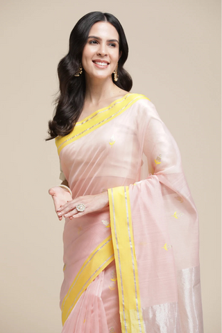 Woman wearing a pink saree with yellow border on a beige background