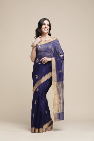 Woman wearing a dark blue saree with gold border on a beige background