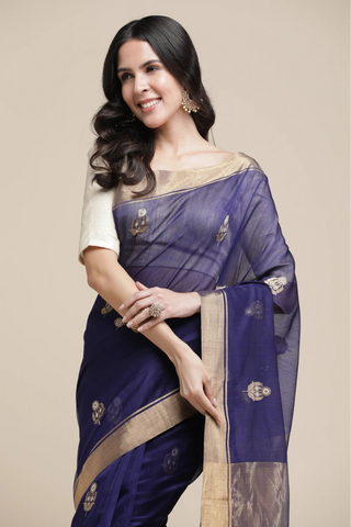 Woman wearing a blue saree with a beige blouse against a beige background