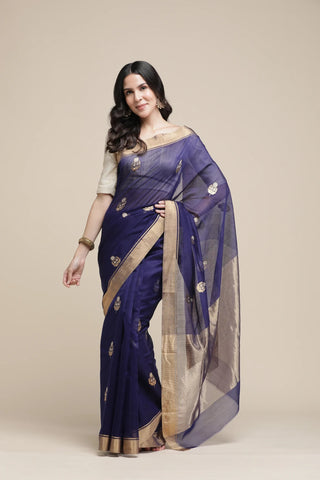 Woman wearing a blue saree with gold details on a beige background