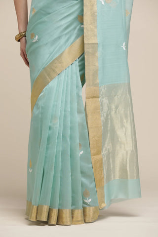 Light blue saree with gold border and patterns on a beige background