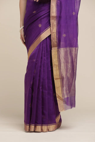 Purple saree with gold border on a beige background
