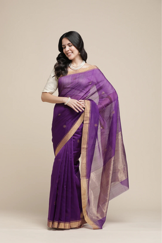 Woman wearing a purple saree with a beige background