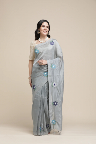Woman wearing a gray saree with floral patterns on a beige background