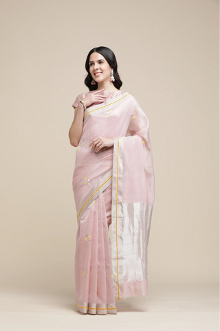 Woman wearing a pink saree with a white blouse against a beige background