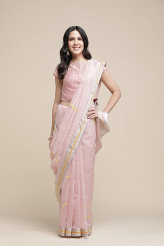 Woman wearing a light pink saree with a plain background
