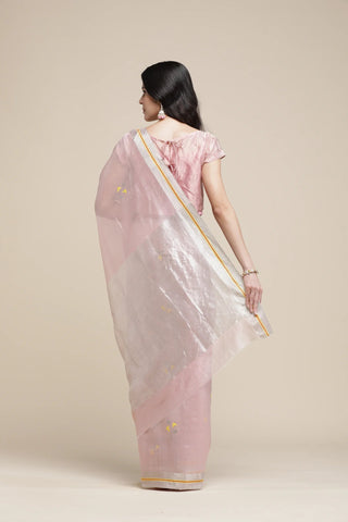 Woman wearing a light pink saree with a subtle pattern on a beige background