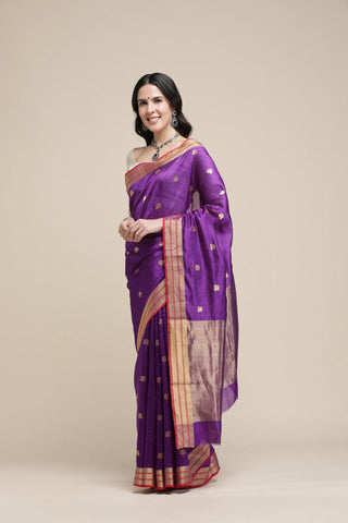 Woman wearing a purple saree with a beige background