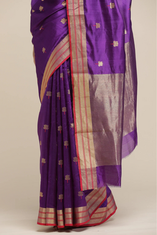 Purple saree with gold and red border on a beige background