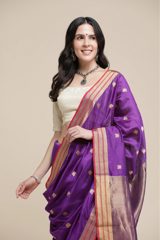 Woman wearing a purple saree with gold border on a beige background