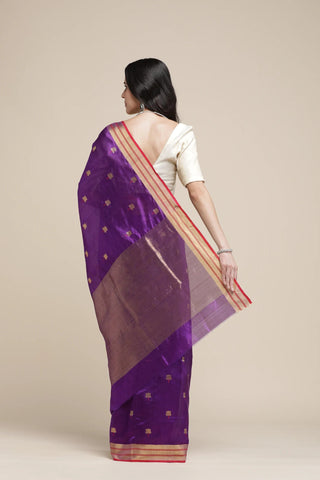 Woman wearing a purple saree with a beige background