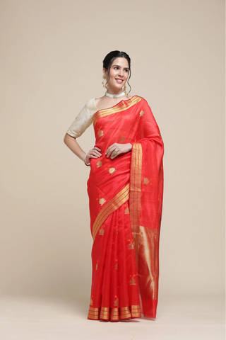 Woman wearing a red saree with gold border on a beige background