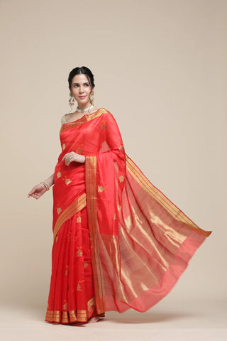 Woman wearing a red saree with gold border on a beige background