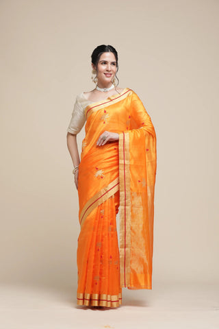 Woman wearing an orange saree with a beige background