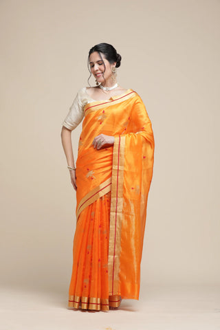 Woman wearing an orange saree with a beige background