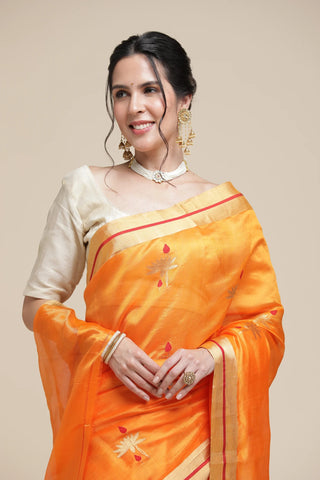 Woman wearing an orange saree with a white blouse against a beige background