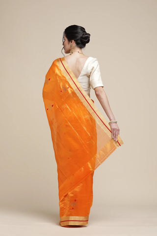 Woman wearing an orange saree with a plain background
