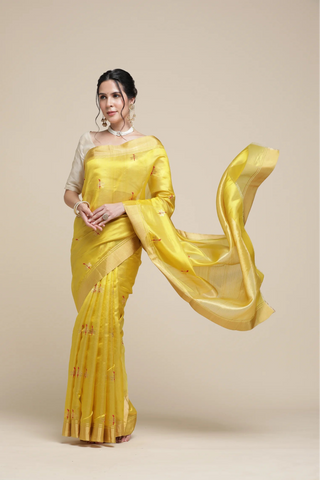 Woman wearing a bright yellow saree with a plain background