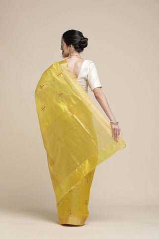 Woman wearing a yellow saree with a plain background