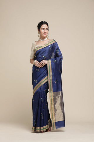 Woman wearing a blue saree with a beige blouse on a beige background