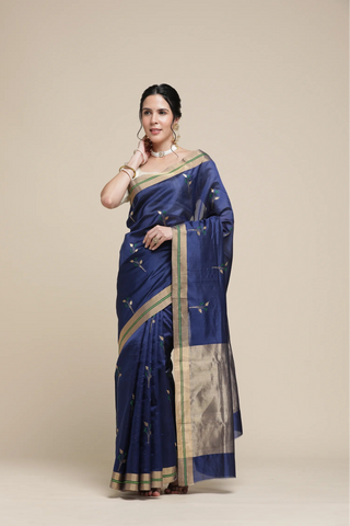 Woman wearing a blue saree with gold border on a beige background