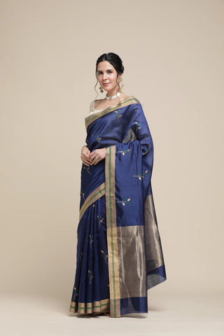 Woman wearing a blue saree with gold border on a beige background