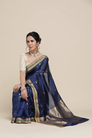Woman wearing a blue saree with a white blouse on a beige background