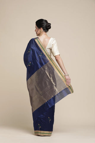 Woman wearing a blue and gray saree with a plain background
