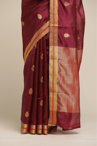Maroon saree with gold border on a beige background