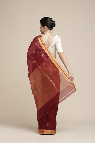Woman wearing a red saree with a white blouse against a beige background