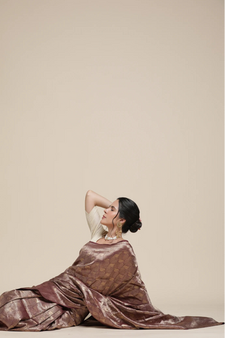 Woman in a brown dress sitting on a white surface with a beige background