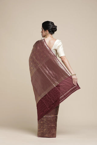 Woman wearing a maroon saree with a beige background