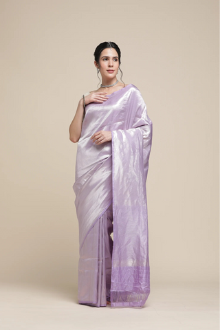 Woman wearing a light purple saree with a plain background