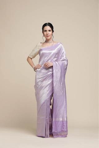 Woman wearing a light purple saree with a beige blouse against a beige background