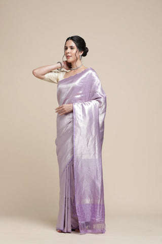 Woman wearing a light purple saree with a plain background